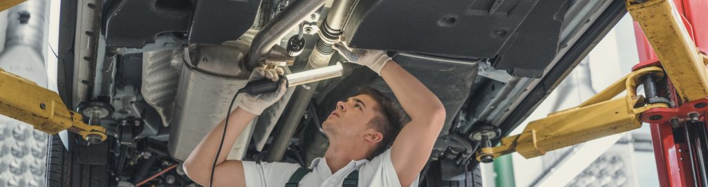 Young mechanic holding a lamp underneath a vehicle - MOT Testing Worthing